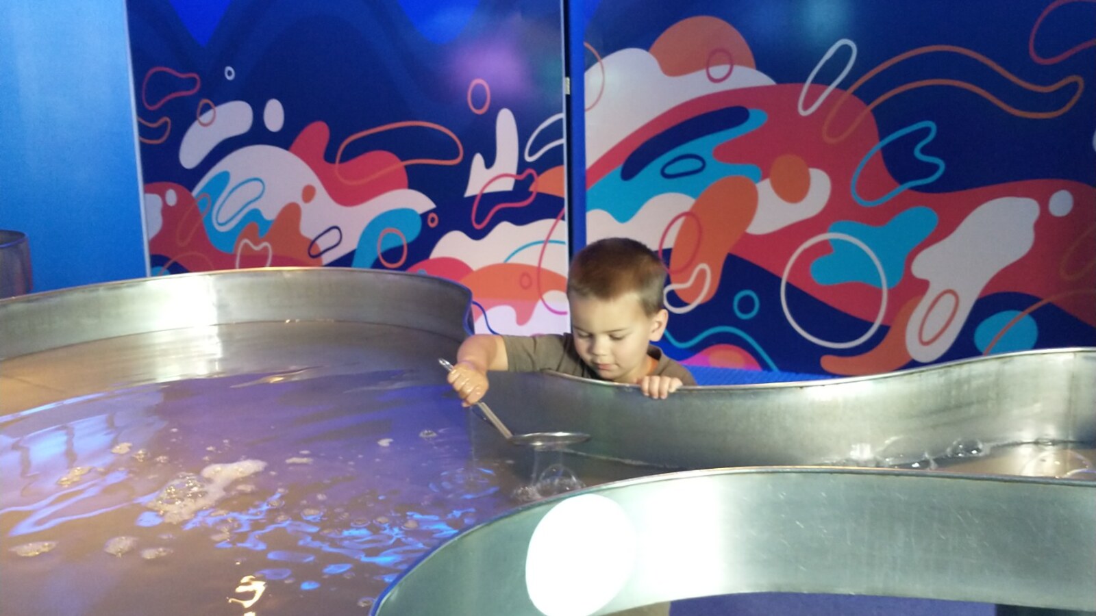 Sam concentrating as he uses a ladle at an interactive water table inside Yaku Water Museum in Quito, Ecuador.