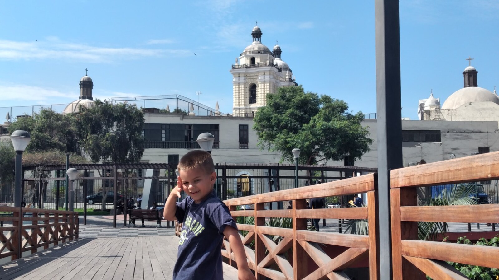 Sam standing on a high wooden pedestrian walkway protected by substantial railings in Lima, Peru.