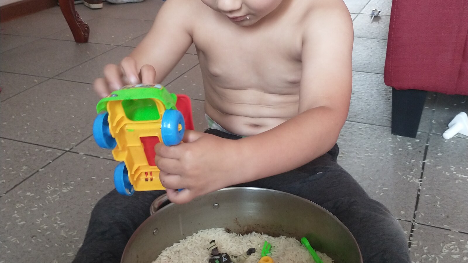 Sam sitting on a living-room floor and playing with a container of rice during his family's time in Quito, Ecuador.