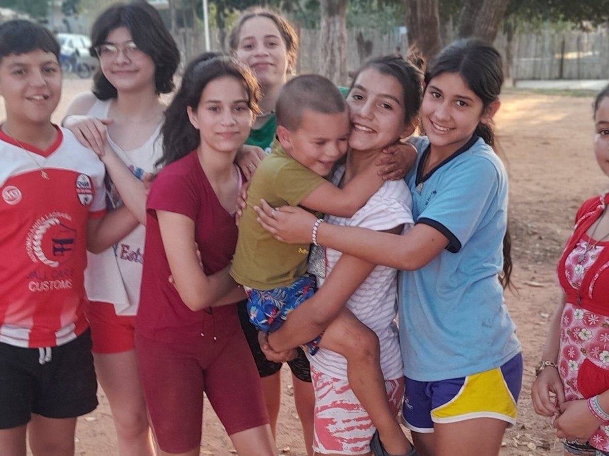 Samuel being warmly embraced and included by a group of young women during his first visit to Paraguay.