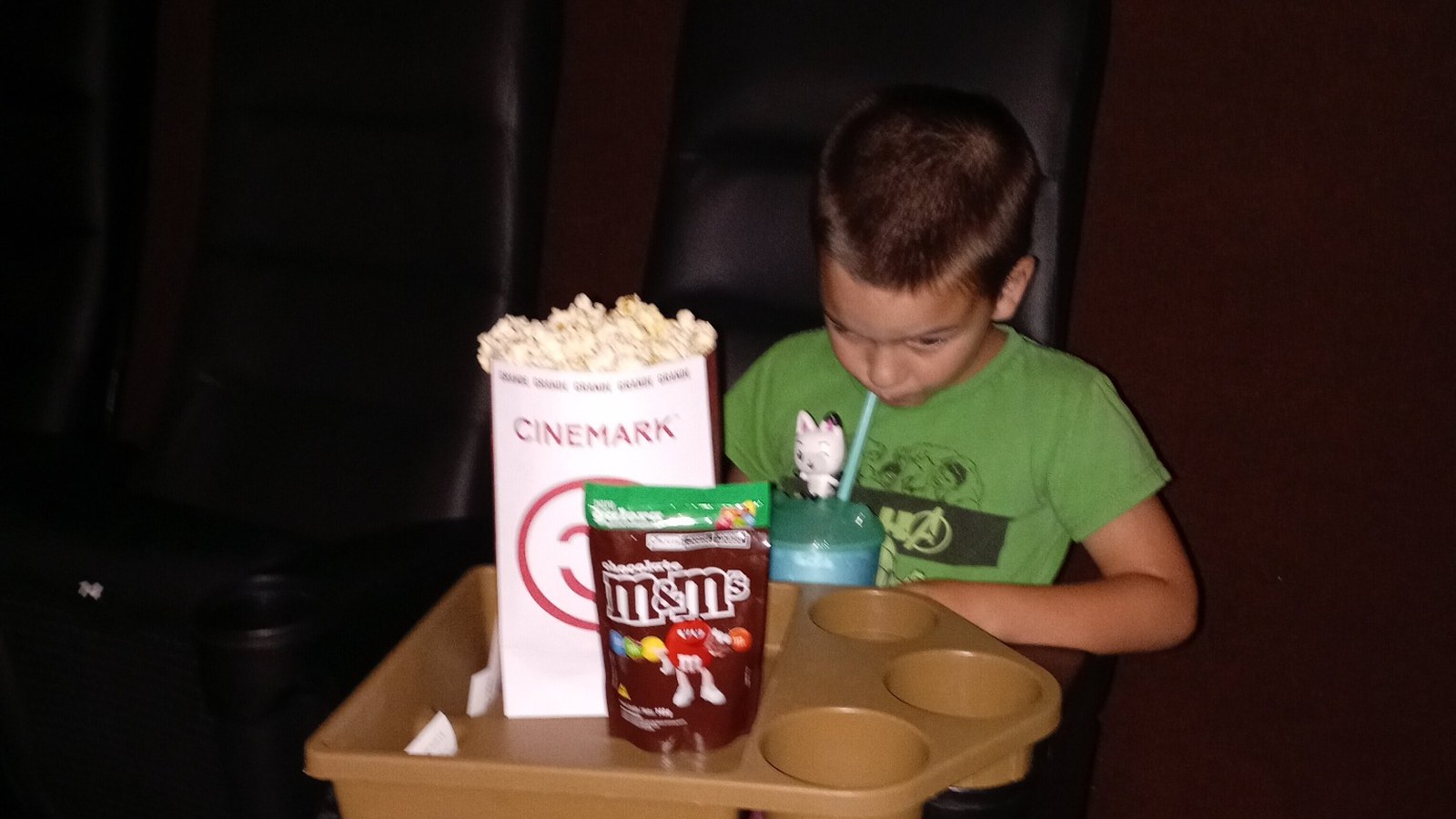 Samuel sitting comfortably in a movie theatre during a family outing.