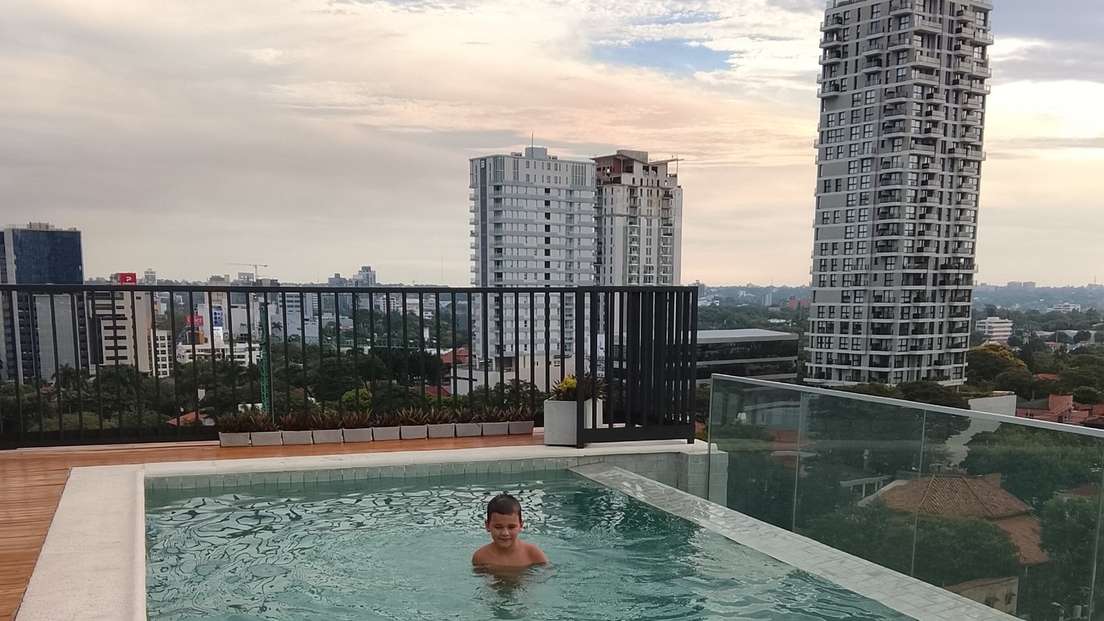 A mother and her autistic son relaxing together beside a rooftop swimming pool.