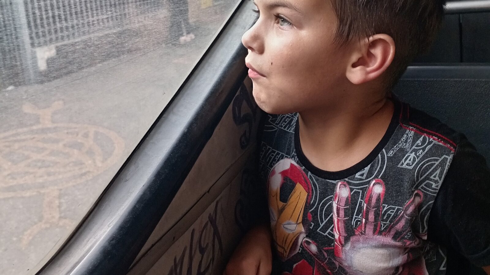 Sam sits comfortably by the window of a public bus after getting on and finding a seat with very little direction.