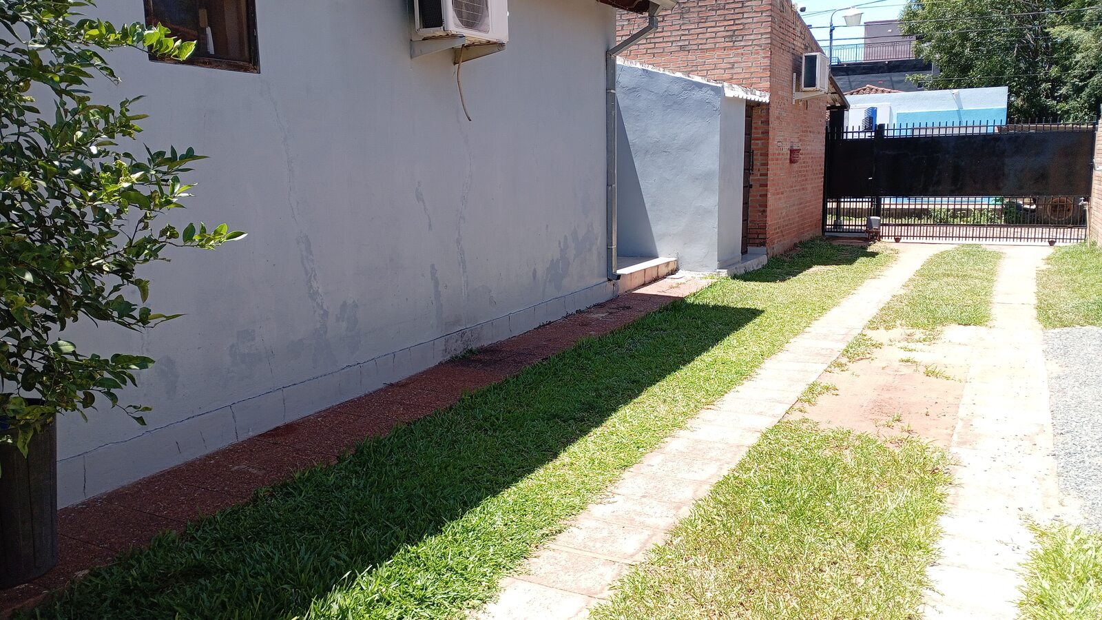 A sunny view of the Mar Azul rental property in San Lorenzo, Paraguay, with its lawn, house, and driveway.