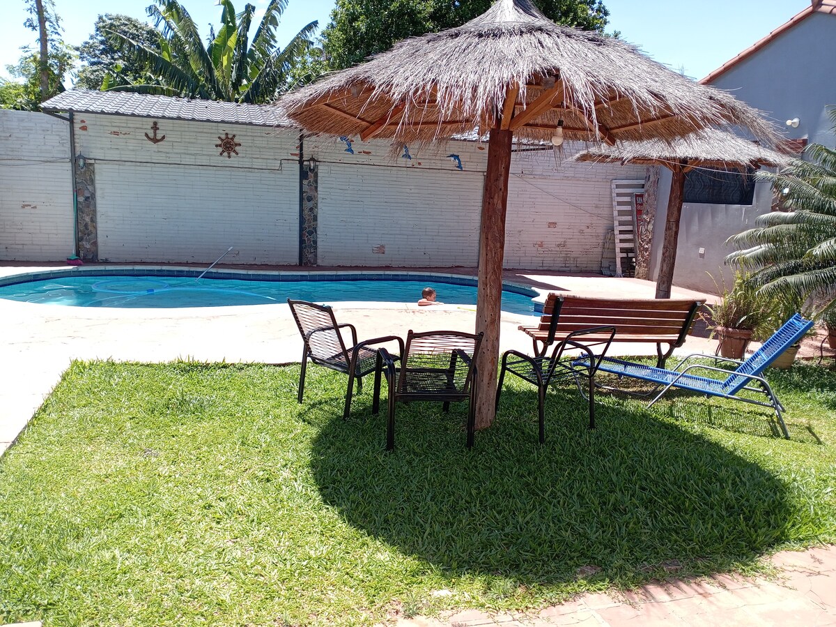 Thatched umbrellas and outdoor seating beside the pool at Mar Azul, with a child visible in the pool near the far edge.