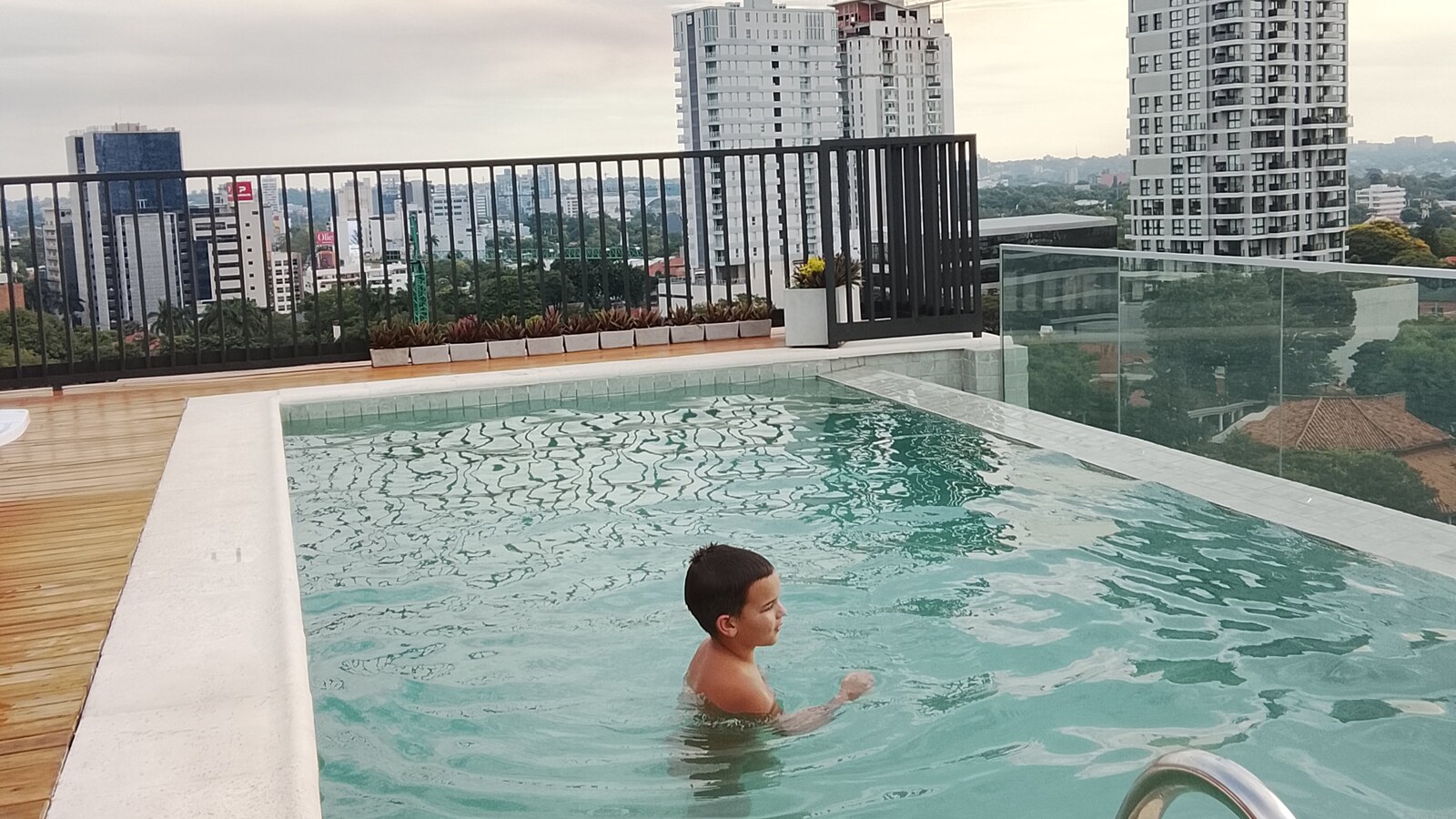 Sam enjoying a rooftop swimming pool with the Asunción skyline behind him.