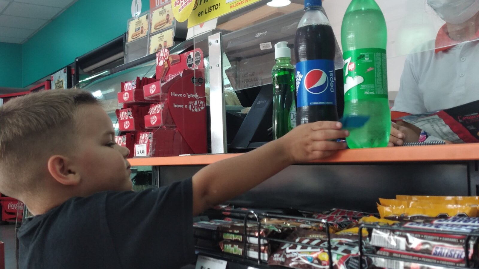 Young Sam placing drink bottles on a checkout counter in a store in Lima, Peru.