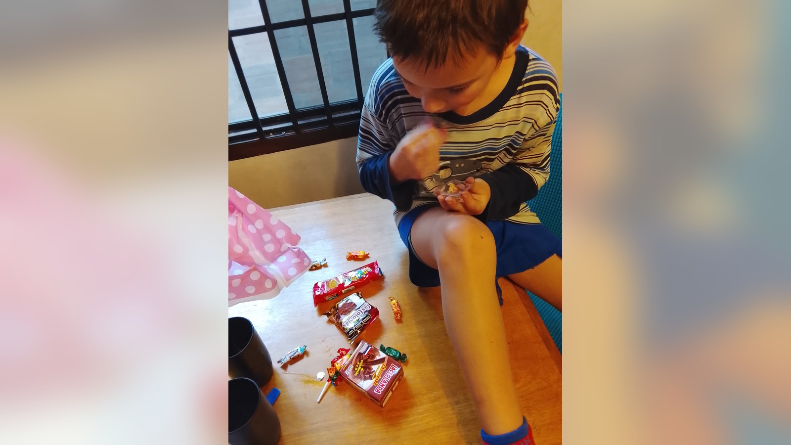 Sam seated on a wooden table with sweets and small packages spread beside him.